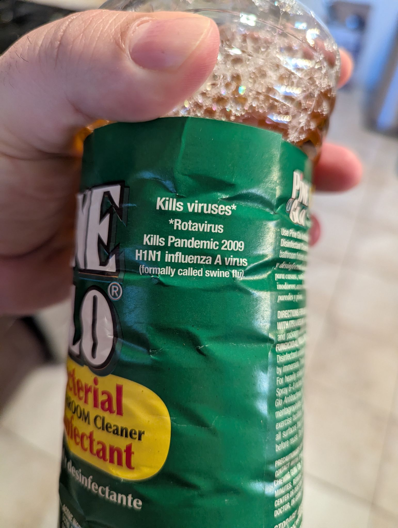 A bottle of pine glo floor cleaner centered on label text that says:  
Kills viruses*
*Rotavirus  
Kills Pandemic 2009  
H1N1 influenza A virus  
(formerly called swine flu)