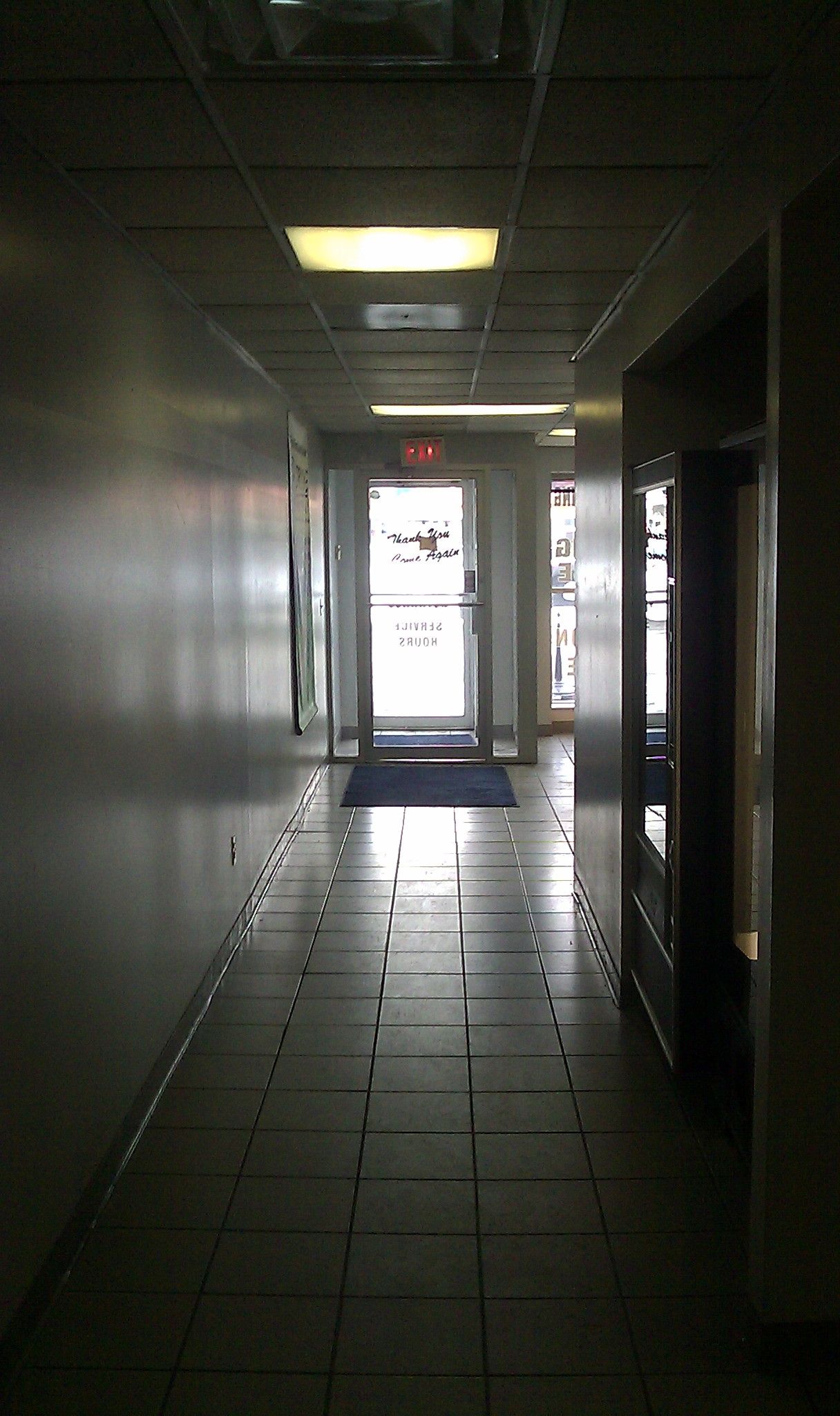 A grainy photo of a corridor that leads up to an exit door.